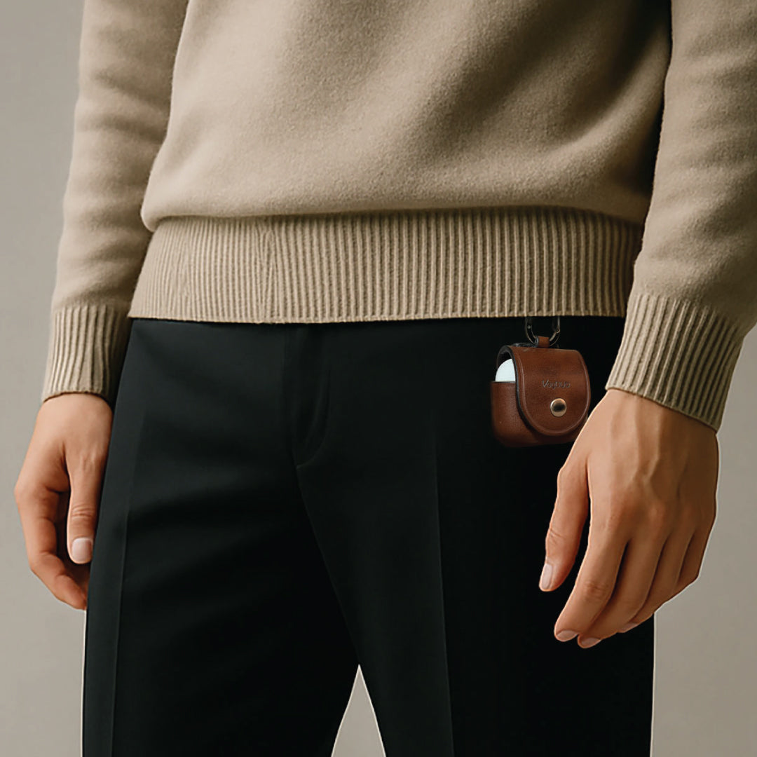 Person wearing a beige sweater and dark pants with a brown leather AirPods 4 case.