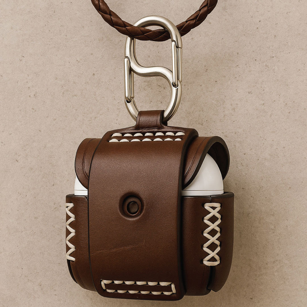 Brown leather case with white stitching and belt-loop design, holding an AirPods 4.