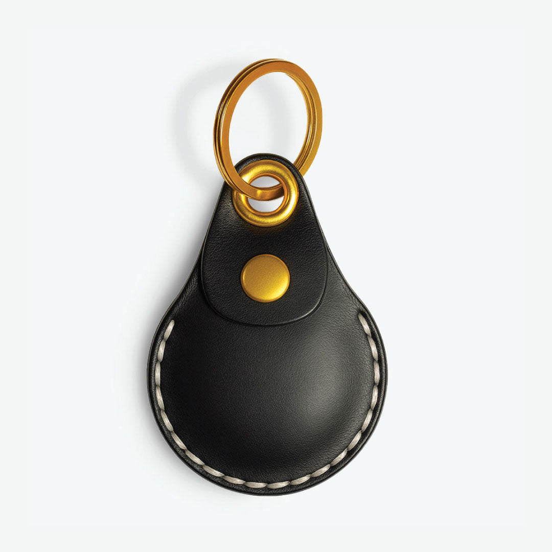 Black AirTag leather case with keychain with gold accents on a white background