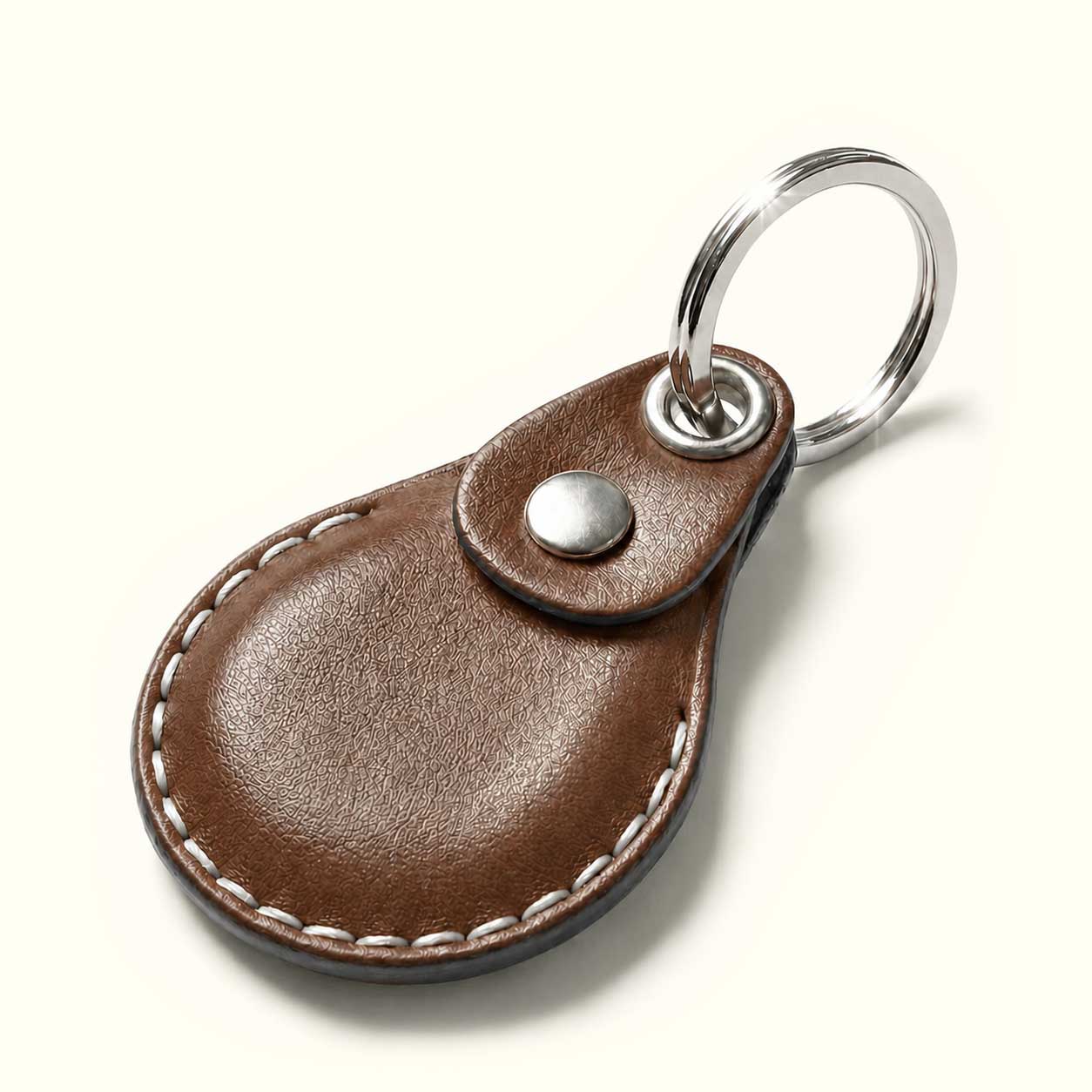 A brown leather keychain design for AirTag with a teardrop-shaped body, white contrast stitching, a snap button closure, and a silver metal key ring on a light cream background.