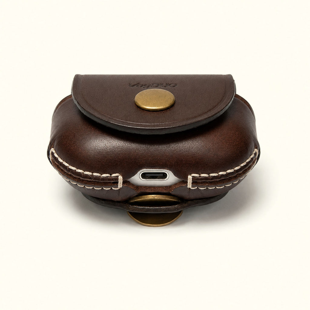 A dark brown leather earbud case with white contrast stitching, a gold snap button, and a visible USB-C charging port, shown on a clean off-white background.