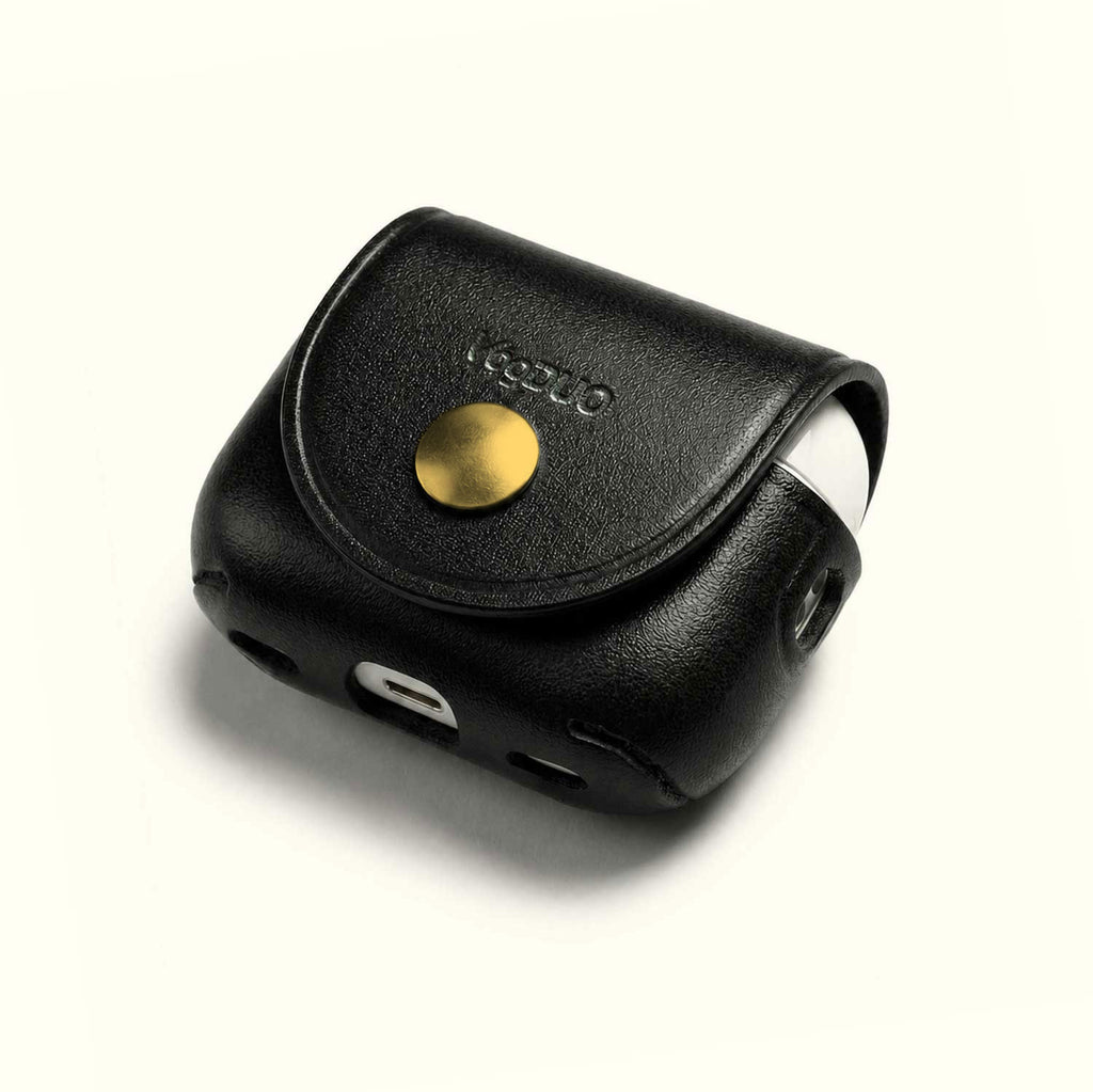 A black textured leather AirPods case with a gold snap button and debossed brand name, shown on a clean off-white background.