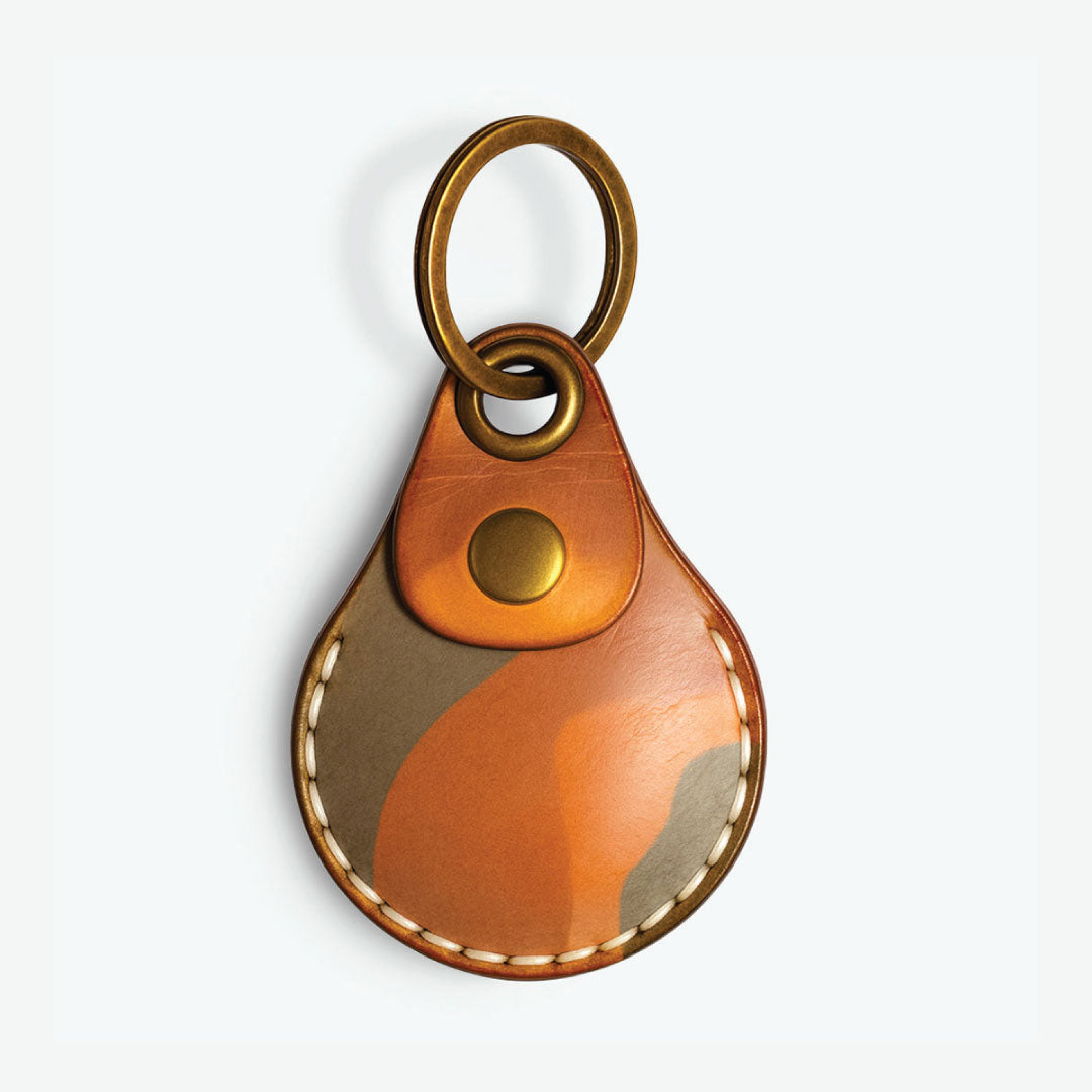 AirTag Leather case with gold ring keychain and button on a white background