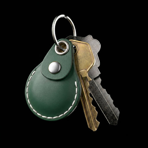 Green AirTag leather key fob with keys on a black background