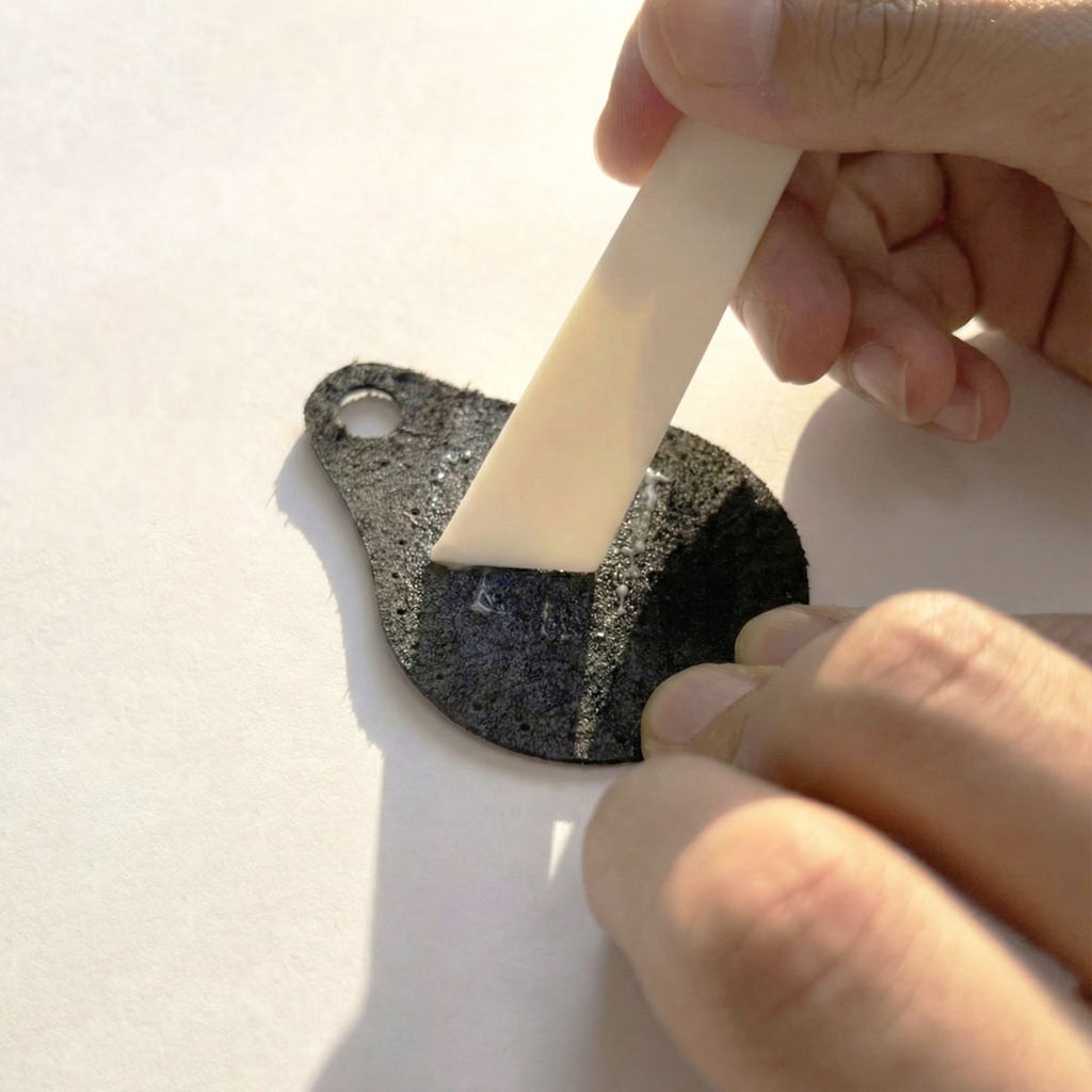 The craftsman is applying the Leather Finish to flatten the leather.