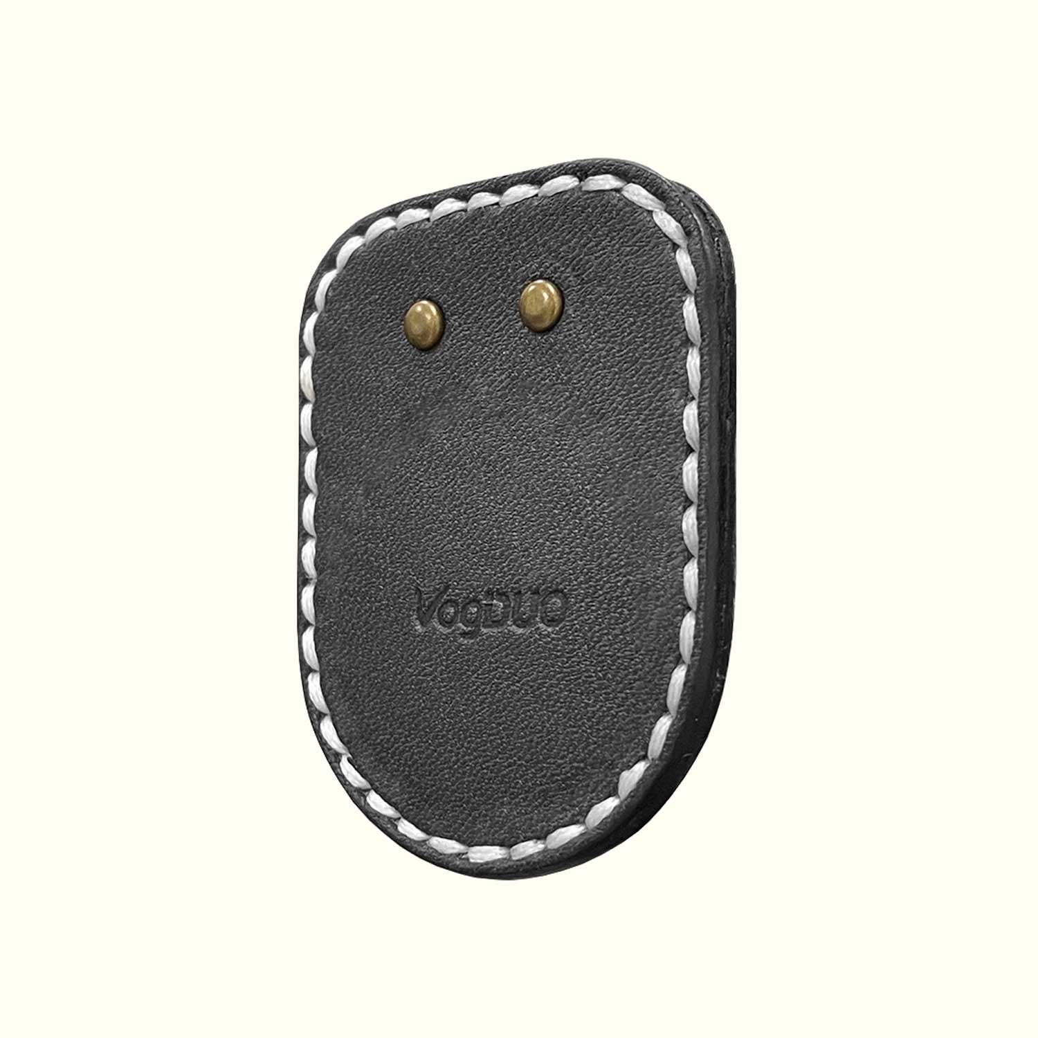 A black leather pouch for AirTag with white contrast stitching and two brass rivets, featuring the embossed brand name 'Vogue' on a light cream background.