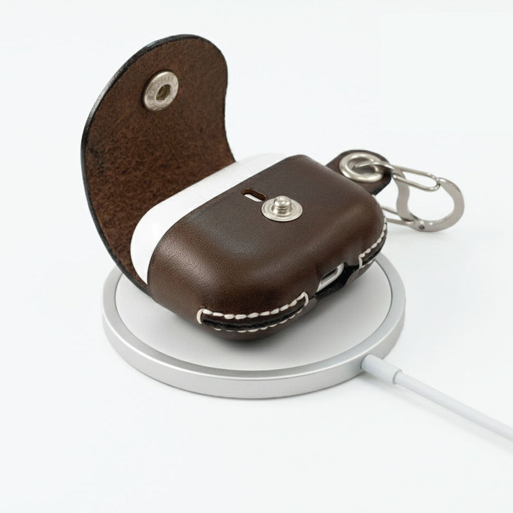 Brown leather AirPods Pro 3 keychain case charging on the Apple MagSafe Wireless Charger.
