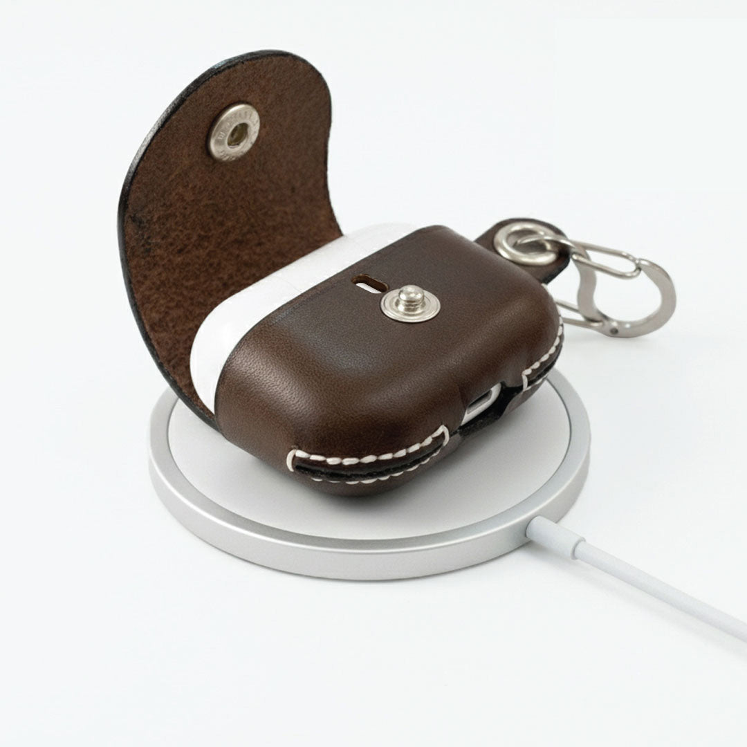 Brown leather AirPods Pro 3 keychain case charging on the Apple MagSafe Wireless Charger.