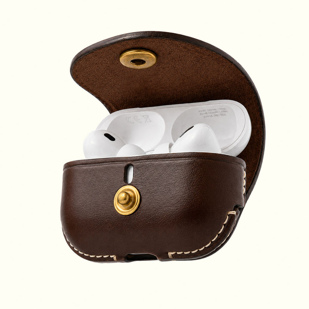A brown leather wireless AirPods Pro case shown open, containing white wireless earbuds. The case has gold-tone metal snap buttons and visible contrast stitching on a plain off-white background.