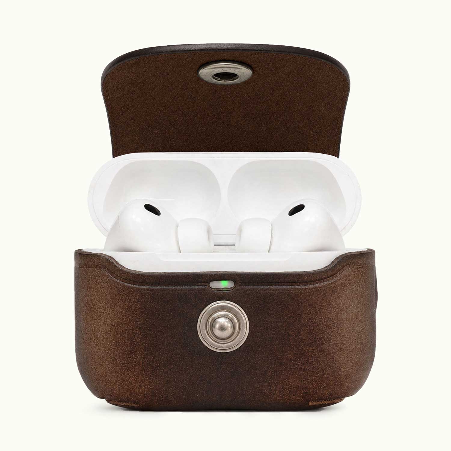 A brown textured leather AirPods Pro 3 charging case shown open, revealing white earbuds inside. The case has a silver metal button on the front and a small green LED indicator light, set against a plain off-white background.