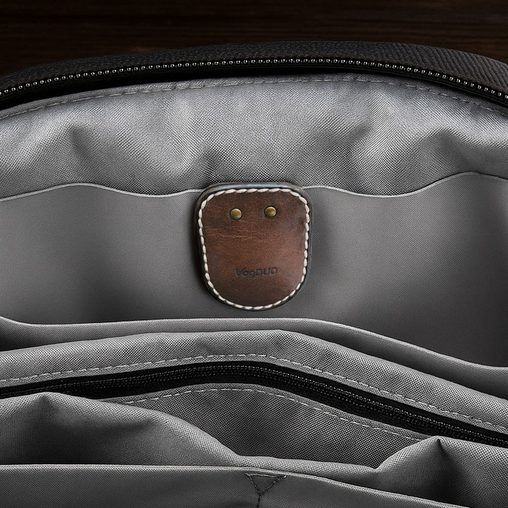 Gray bag with a brown leather AirTag Leather Case and gold brooch pin