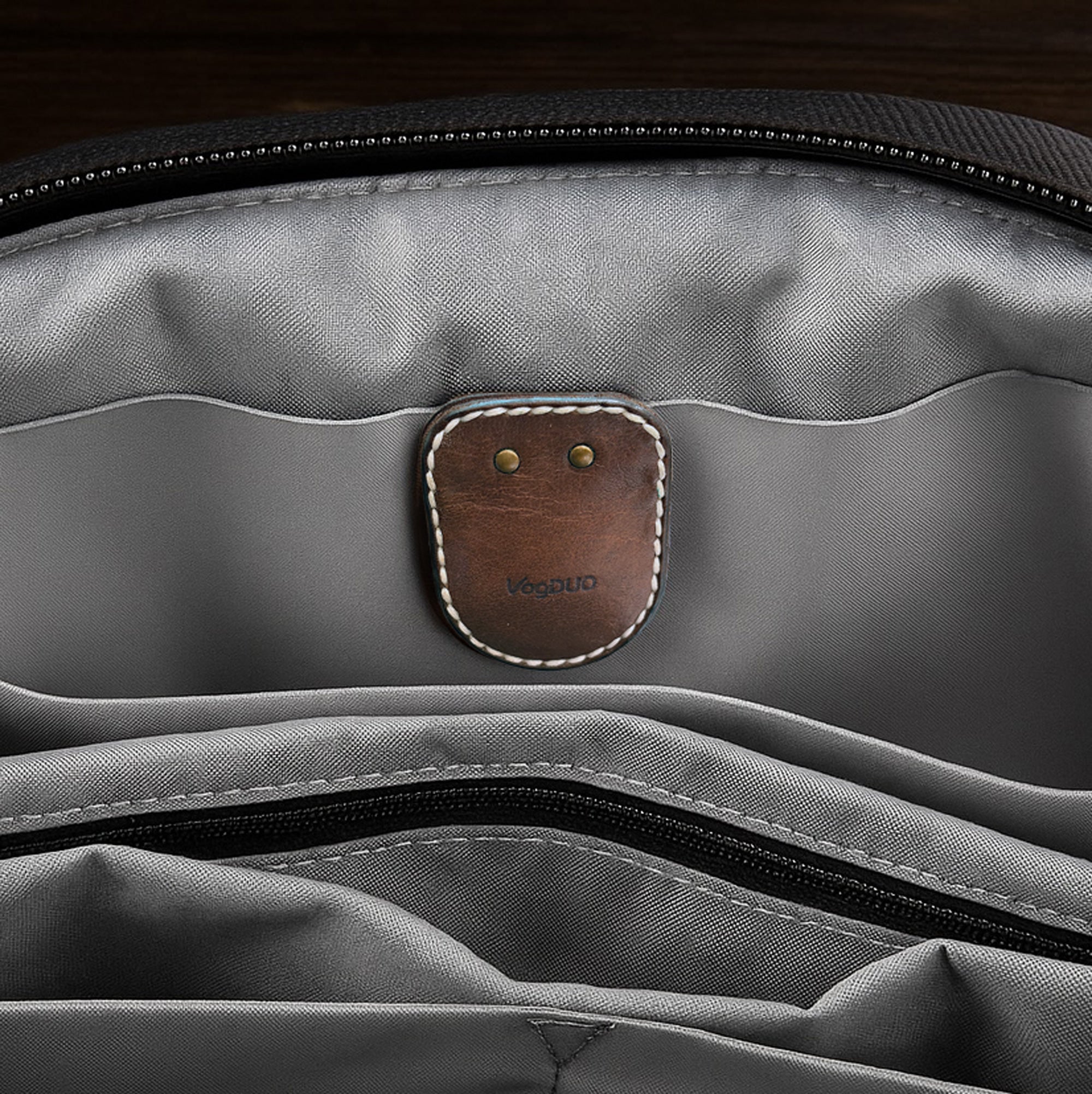 Gray bag with a brown leather AirTag Leather Case and gold brooch pin