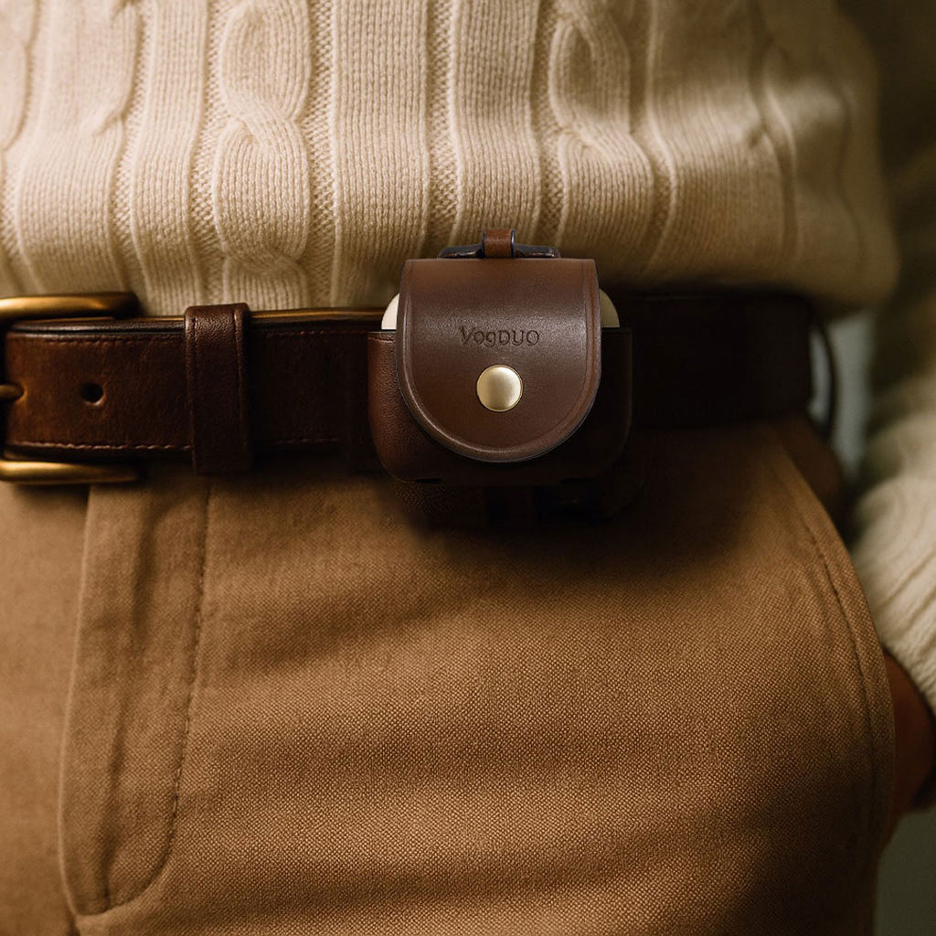 AirPods 4 brown leather case worn on a person's waist with the belt-loop design, against a neutral background.