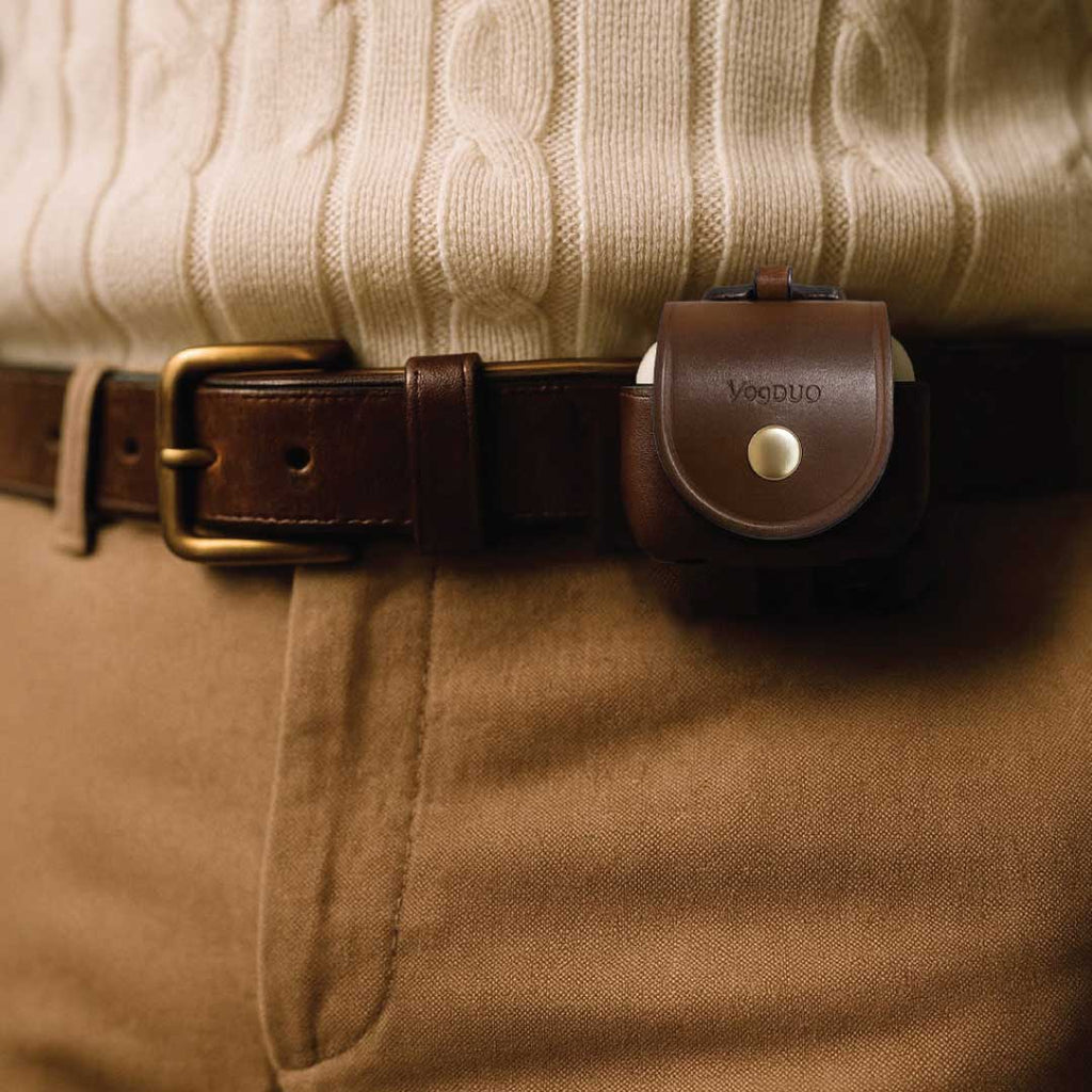 AirPods 4 brown leather case worn on a person's waist with the belt-loop design, against a neutral background.