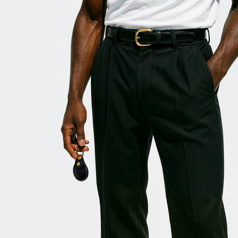 Person wearing black dress pants with a white shirt, casually carrying a VogDUO AirTag Leather case on his way home, showing stylish and confidence.